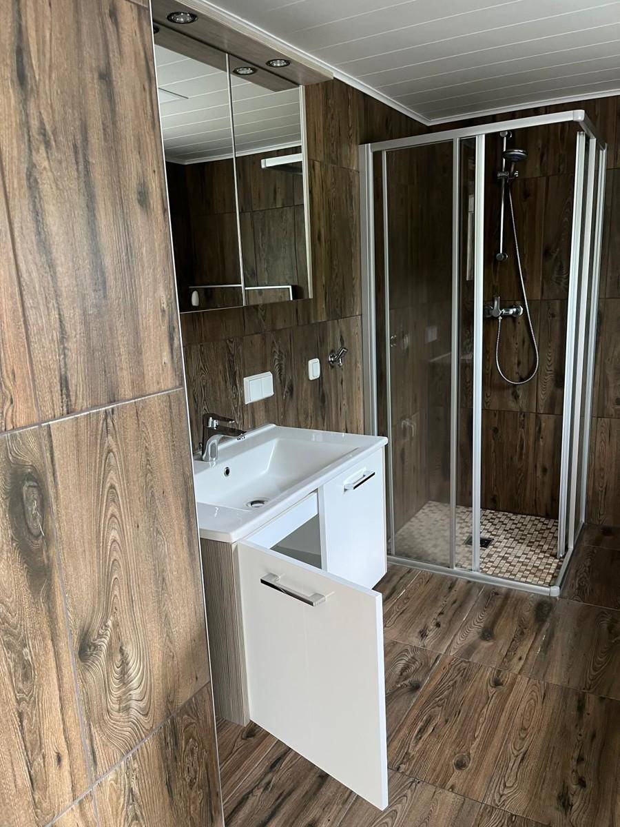 Modernes Badezimmer mit Duschkabine, Waschbecken und Spiegelschrank.