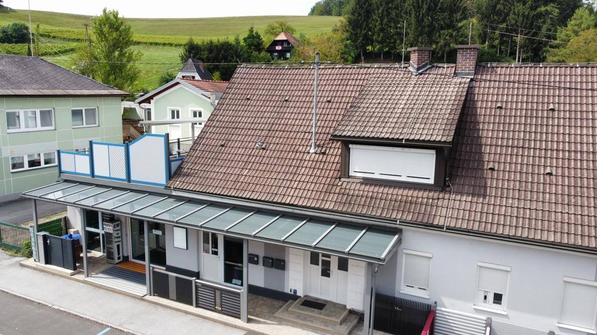 Nahaufnahme des Gebäudes aus der Vogelperspektive mit Dach, Vordach und angrenzender Straße.