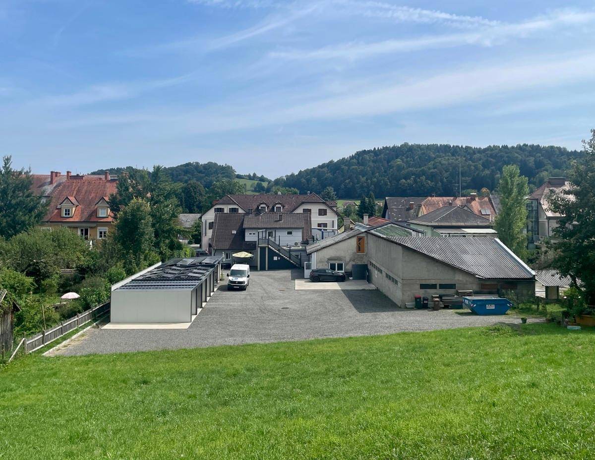 Weitläufiger Außenbereich mit Parkplätzen, Carports und Blick auf die umliegende Hügellandschaft.