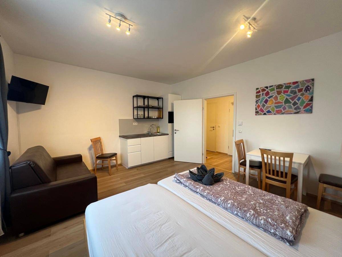 Gemütlicher Wohnbereich mit Bett, Sofa, Esstisch und integrierter Küchenzeile.
