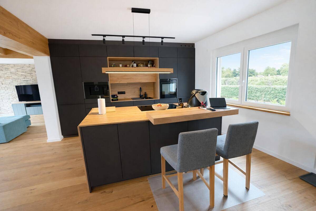 Moderne Küche mit dunklen Schränken, Holztheke und integrierten Geräten.