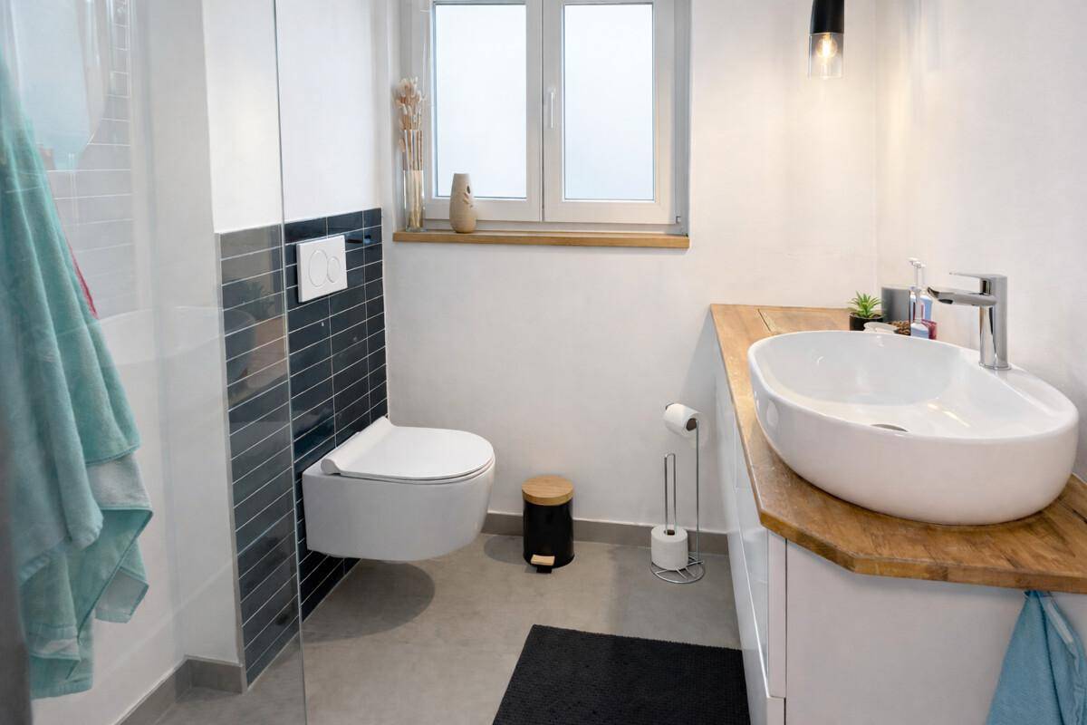 Modernes Badezimmer mit Dusche, Waschtisch und Fenster für Tageslicht.