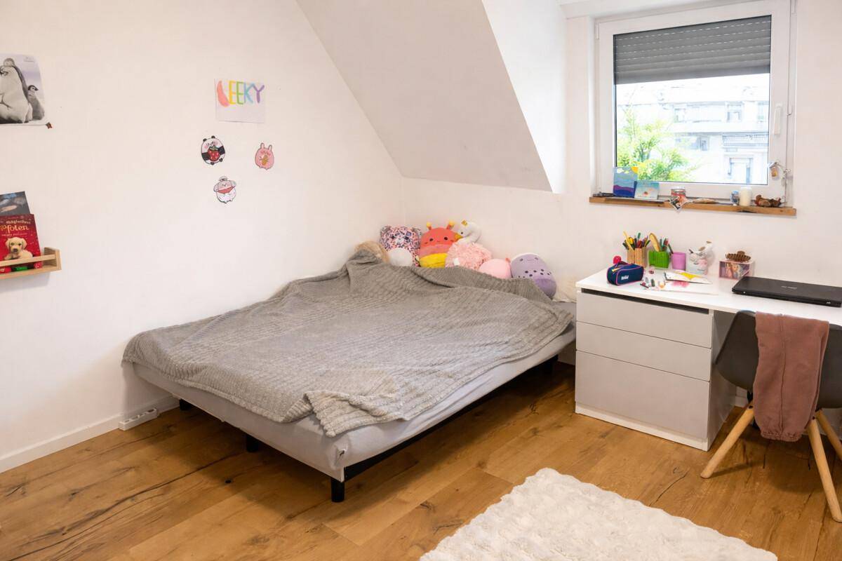 Kinderzimmer im Dachgeschoss mit Bett, Schreibtisch und viel Tageslicht.