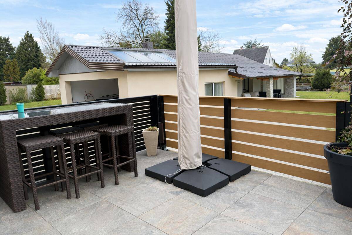 Geräumige Terrasse mit Outdoor-Möbeln, Sonnenschirm und Blick auf die Umgebung.