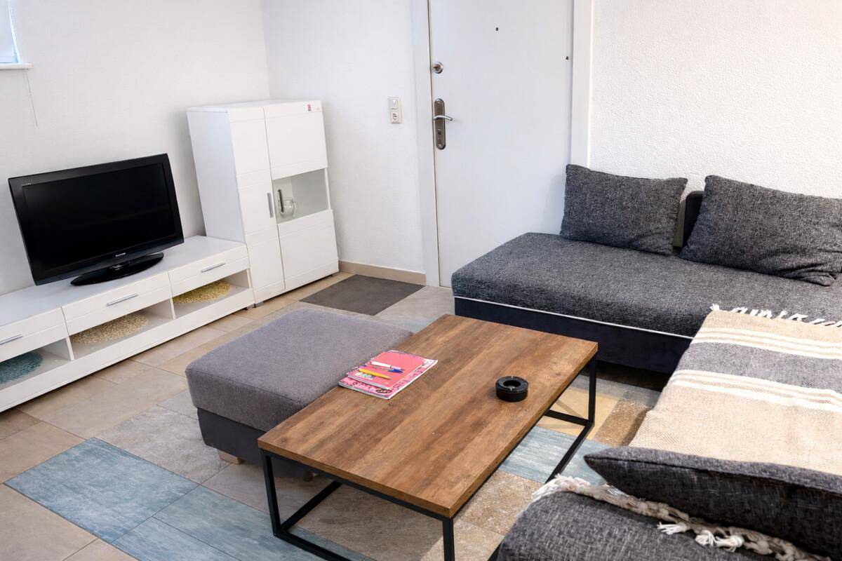Gemütliches Wohnzimmer im Untergeschoss mit Sofa, Couchtisch und Fernseher.