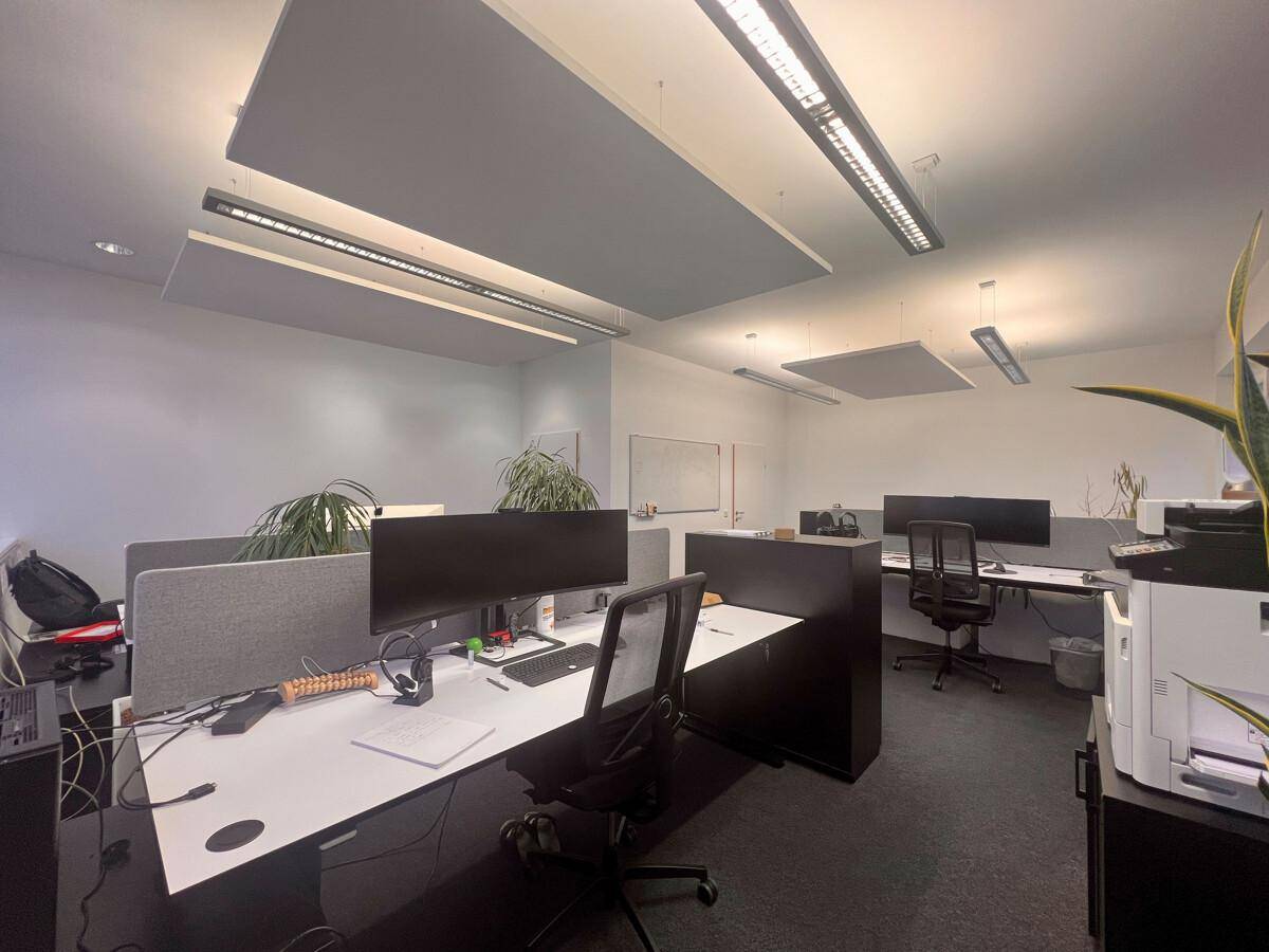 Moderner Büroraum mit mehreren Arbeitsplätzen, Schreibtischen und ergonomischen Stühlen, ausgestattet mit Schallschutzplatten.
