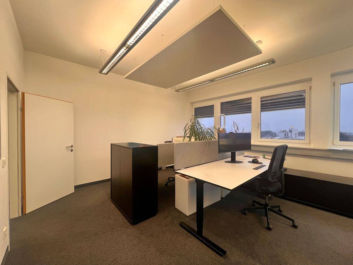 Heller Büroraum mit einem Arbeitsplatz, Schreibtisch und ergonomischem Stuhl, ergänzt durch Schallschutzplatten an der Decke.