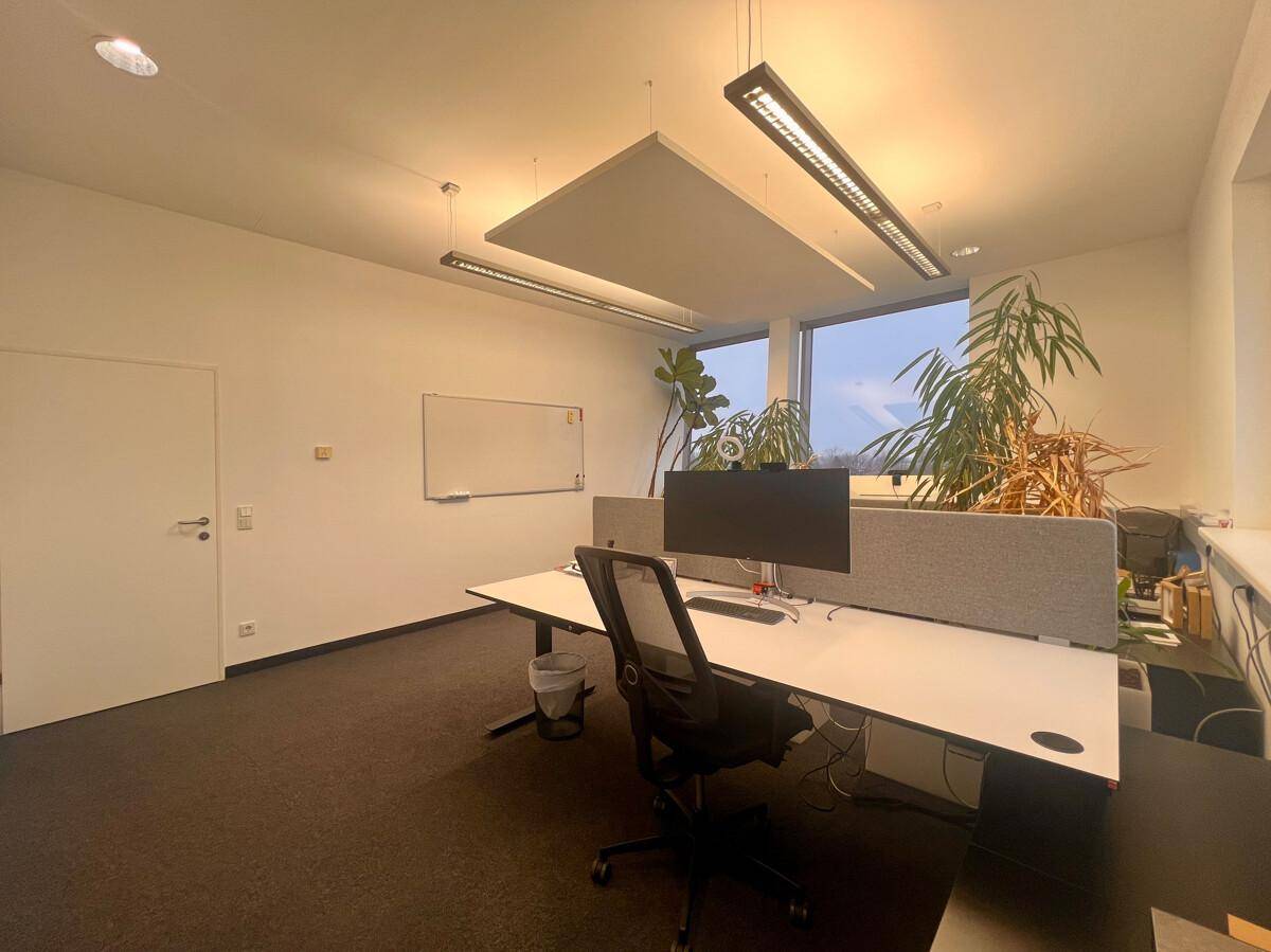 Heller Büroraum mit einem Arbeitsplatz, Schreibtisch und ergonomischem Stuhl, mit Blick auf die Umgebung.