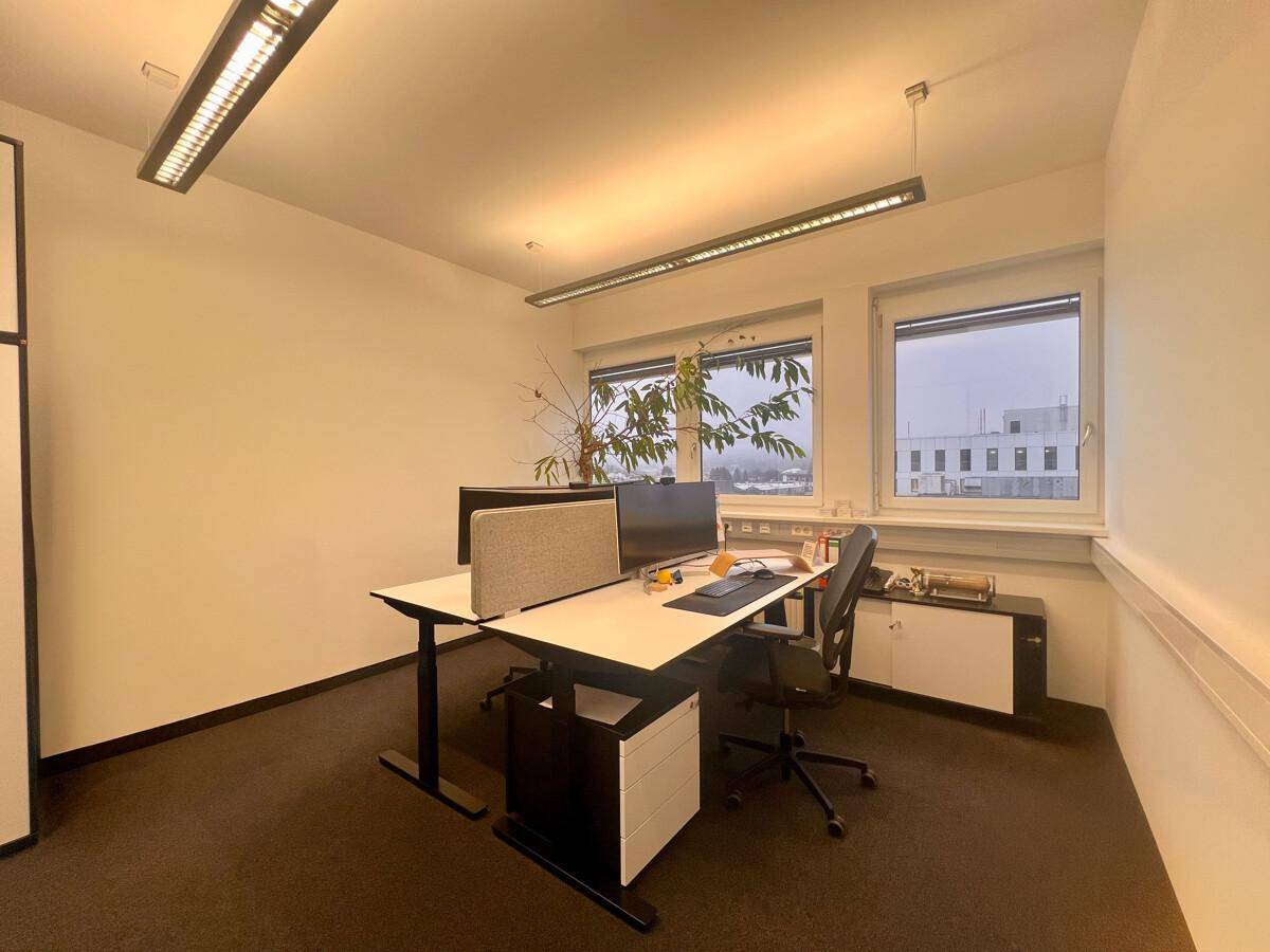 Heller Büroraum mit zwei Arbeitsplätzen, Schreibtischen und ergonomischen Stühlen, mit Blick nach draußen.
