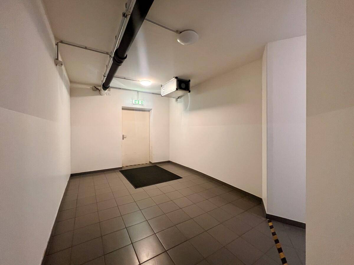 Kellerraum mit Fliesenboden und sichtbaren Rohren an der Decke, dient als Zugangsbereich.