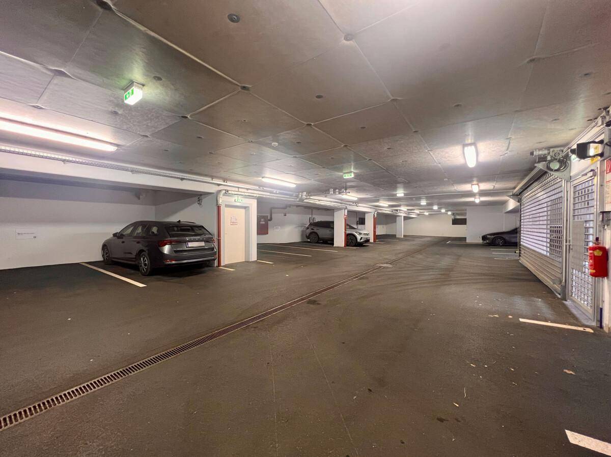Helle Tiefgarage mit mehreren Parkplätzen und Autos, gut beleuchtet und sicher.