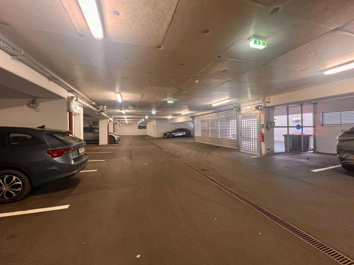 Geräumige Tiefgarage mit mehreren Parkplätzen und Autos, gut beleuchtet und sicher.