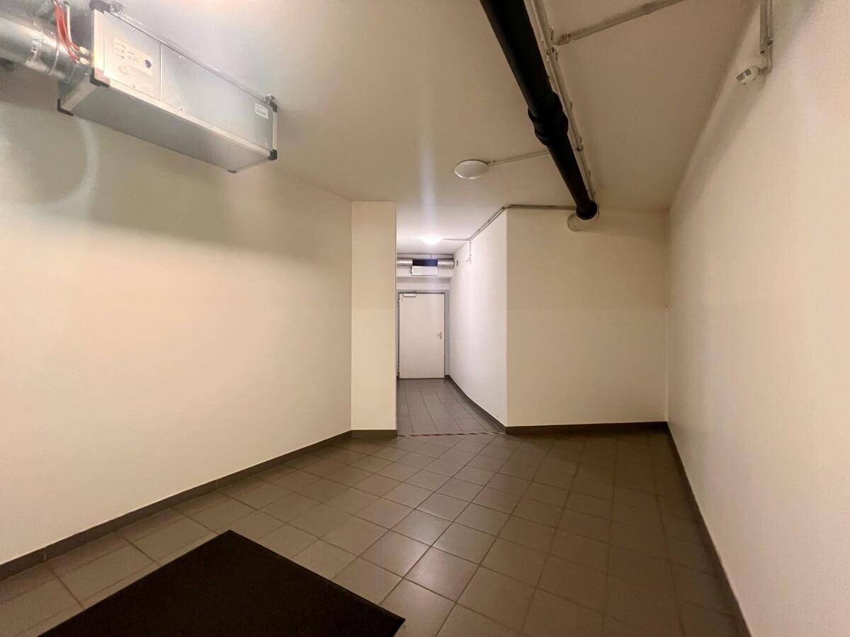 Kellerraum mit Fliesenboden und sichtbaren Rohren an der Decke, dient als Zugangsbereich.