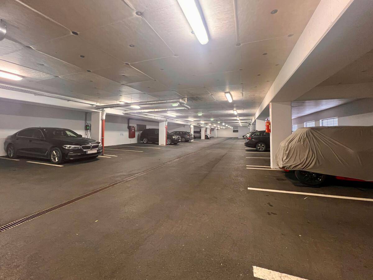 Geräumige Tiefgarage mit mehreren Parkplätzen und Autos, gut beleuchtet und sicher.