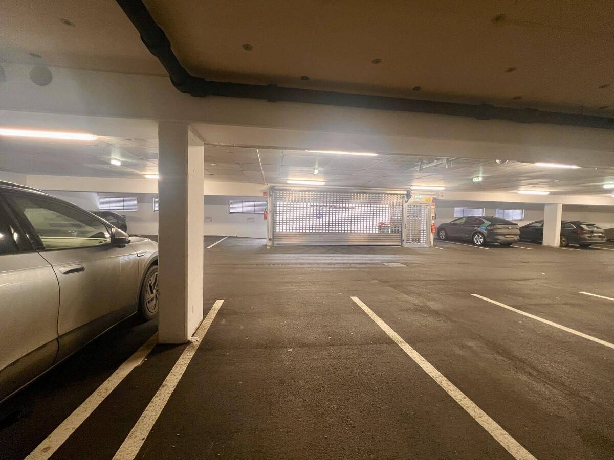 Helle Tiefgarage mit mehreren Parkplätzen und Autos, gut beleuchtet und sicher.