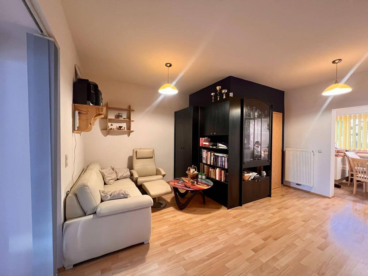 Wohnzimmer mit Sofa, Bücherregal und hellem Holzboden in modernem Stil.