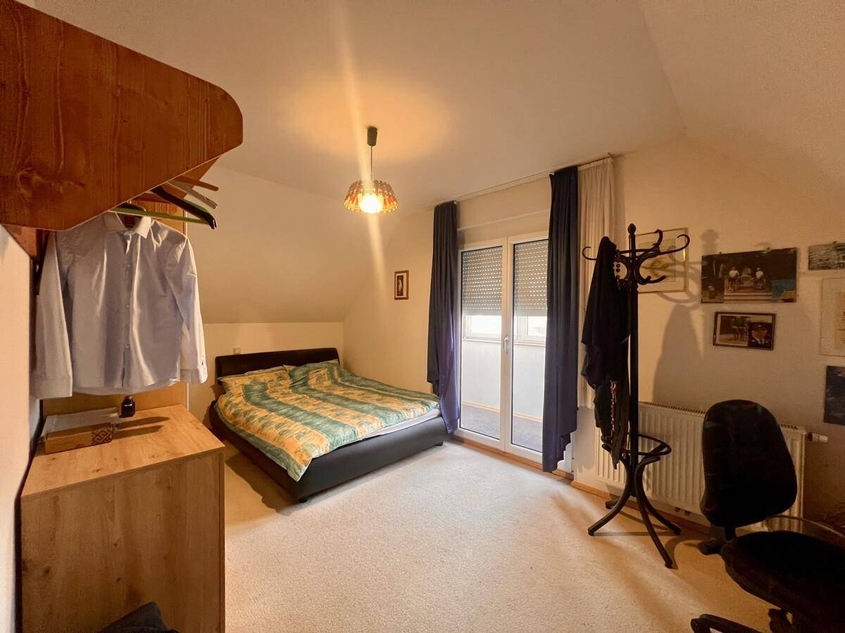 Schlafzimmer mit Dachschräge, Teppichboden und Fenster für natürliches Licht.