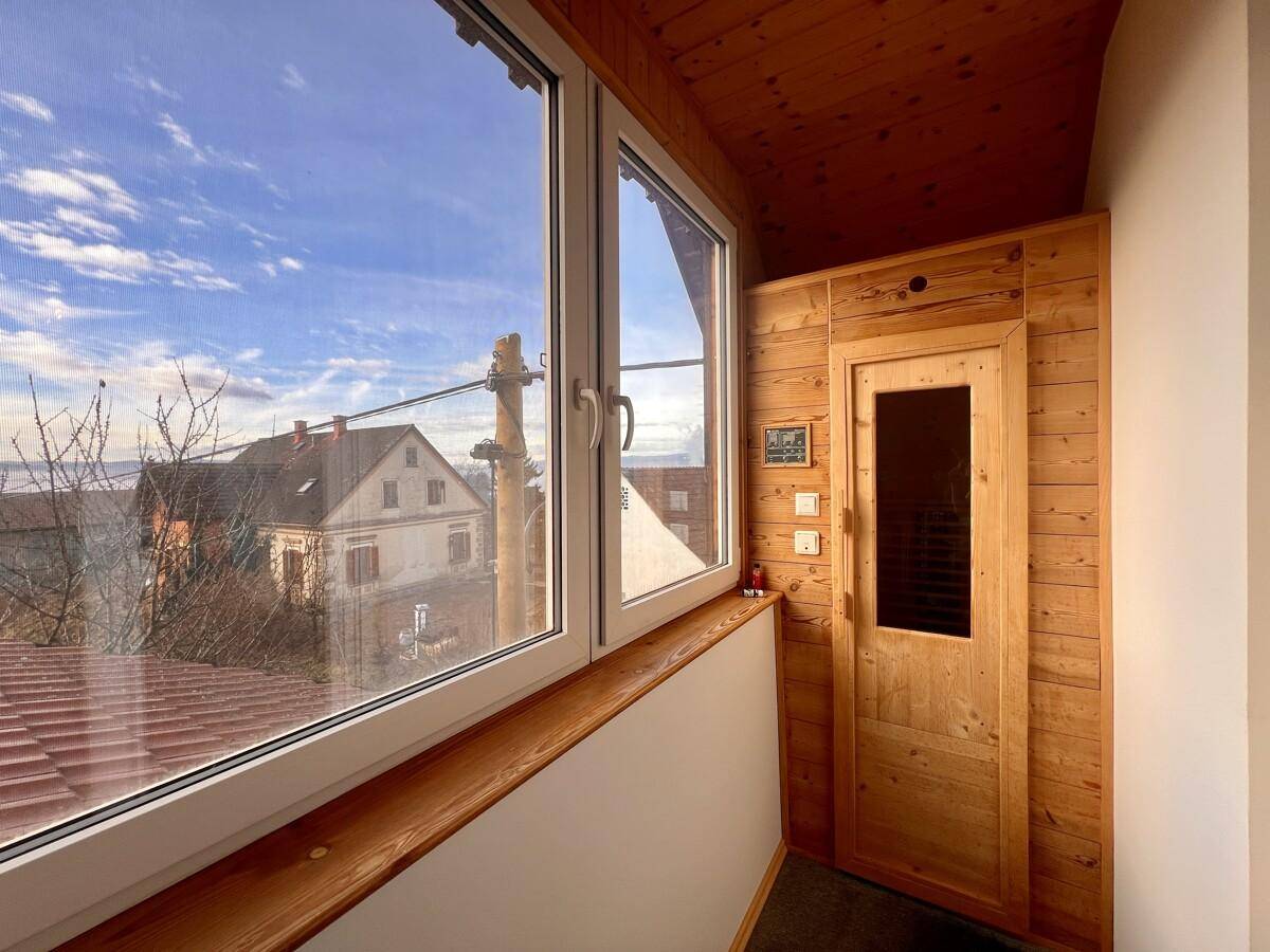 Kleine Sauna mit Holzverkleidung und Fensterblick in einem Wellnessbereich.