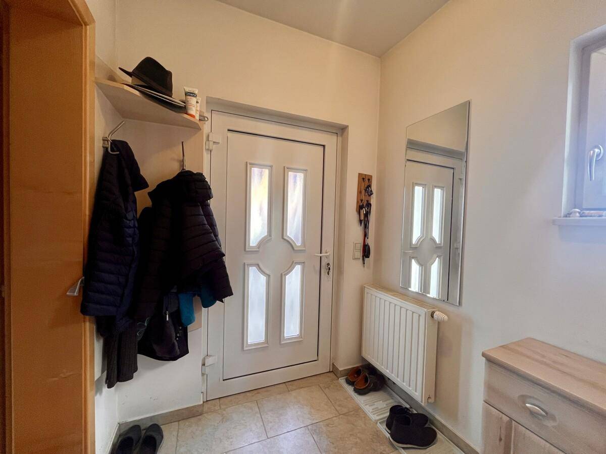 Eingangsbereich mit Fliesenboden, Garderobe und Spiegel an der Wand.