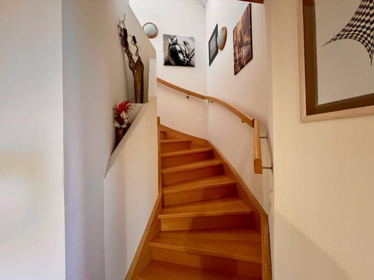 Helle Holztreppe mit Handlauf, die in die obere Etage des Hauses führt.