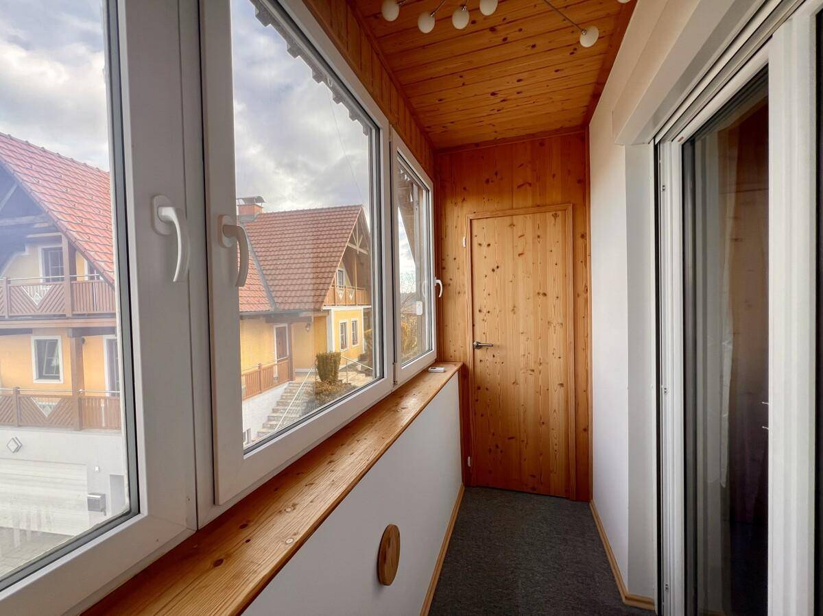 Verglaste Loggia mit Holzdecke und Blick auf die Umgebung, ideal zum Entspannen.
