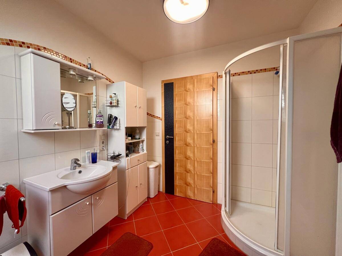 Badezimmer mit Duschkabine, Waschbecken und Spiegelschrank in funktionalem Design.