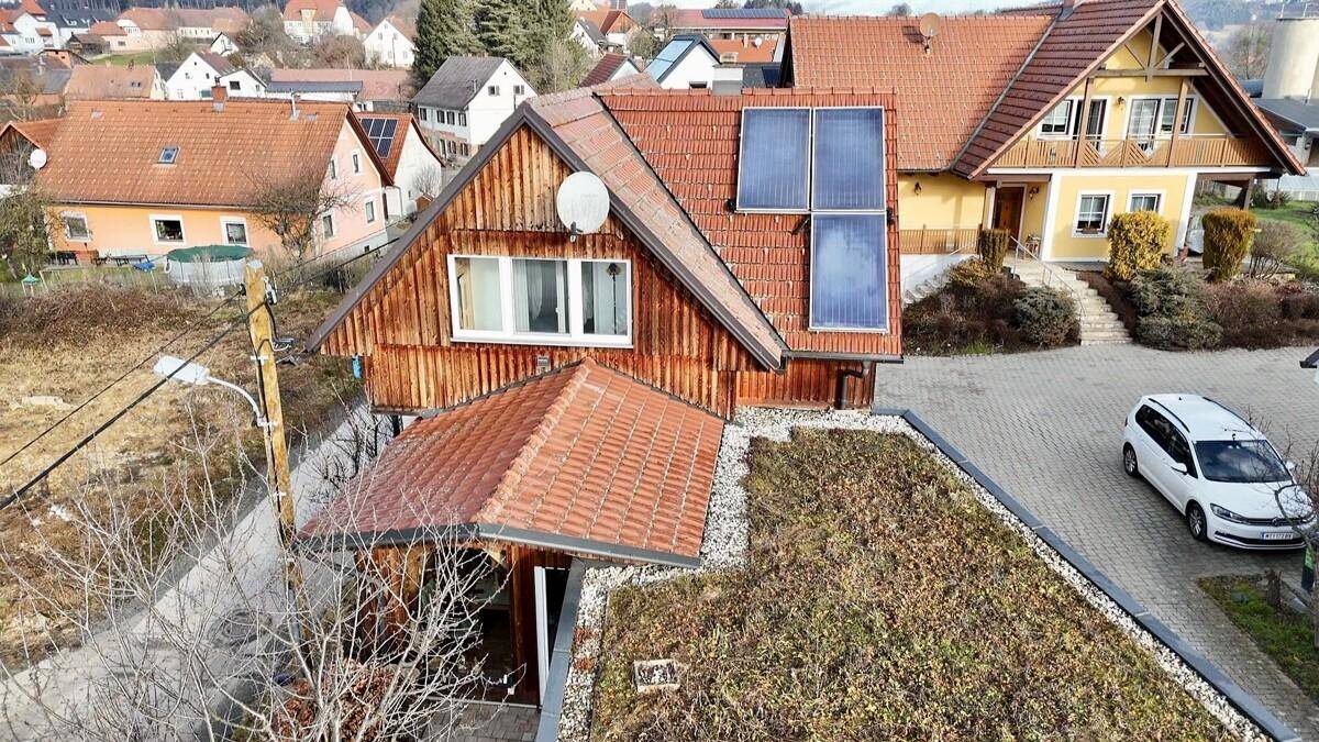Luftaufnahme des Hauses mit Photovoltaikanlage und begrüntem Anbau in sonniger Lage.
