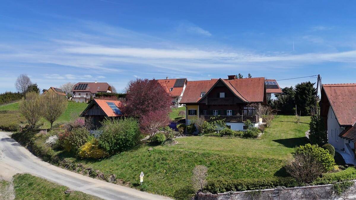 Weitläufige Luftaufnahme einer ländlichen Wohngegend mit Häusern, Gärten und einer Straße.
