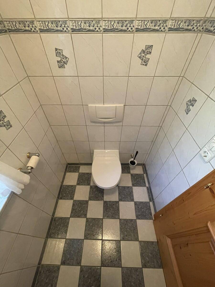 Kleines Gäste-WC mit Wand-WC und markantem schwarz-weißem Fliesenboden.