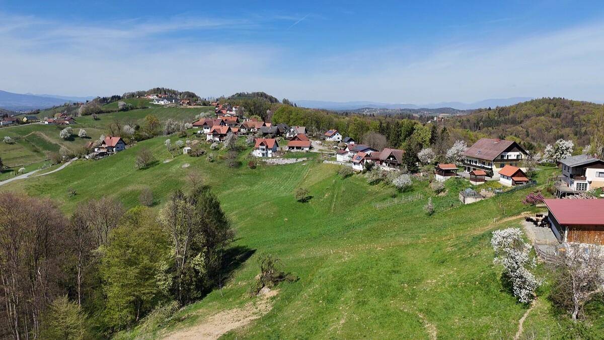 Weitläufige Landschaftsaufnahme mit grünen Hügeln, Wäldern und verstreuten Häusern.