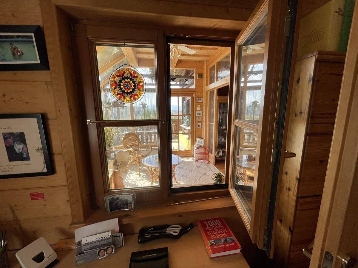 Blick vom Arbeitszimmer durch ein Fenster in den sonnigen Wintergarten.