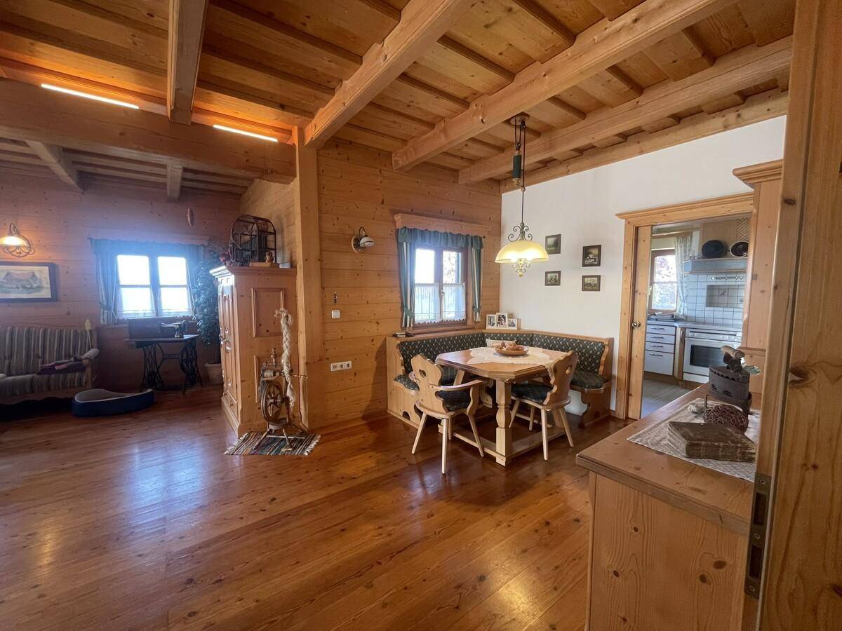 Traditioneller Wohn-Essbereich mit Holzboden, Kachelofen und gemütlicher Sitzecke.