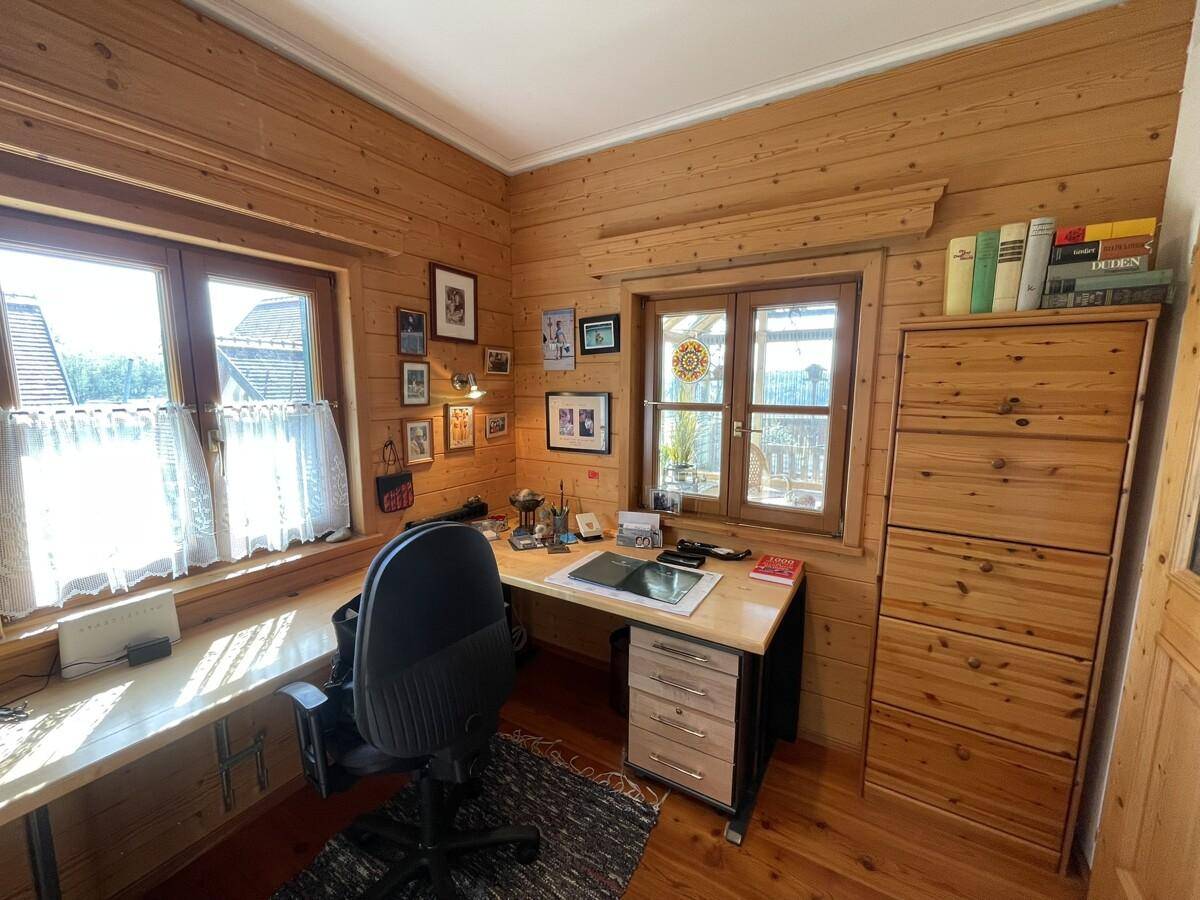 Helles Arbeitszimmer mit Holzwänden, Schreibtisch und Blick ins Grüne.