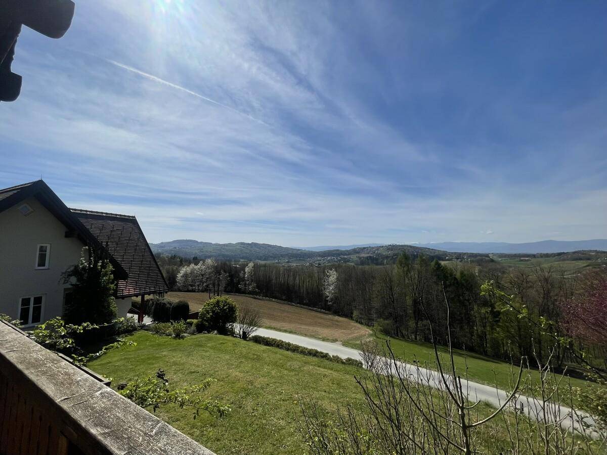 Malerischer Ausblick von der Terrasse auf die weite, grüne Landschaft und den blauen Himmel.