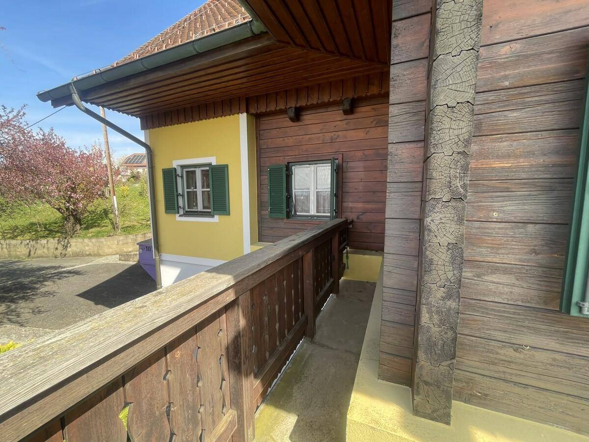 Balkon mit Holzgeländer und Blick auf die gelbe Fassade des Hauses.