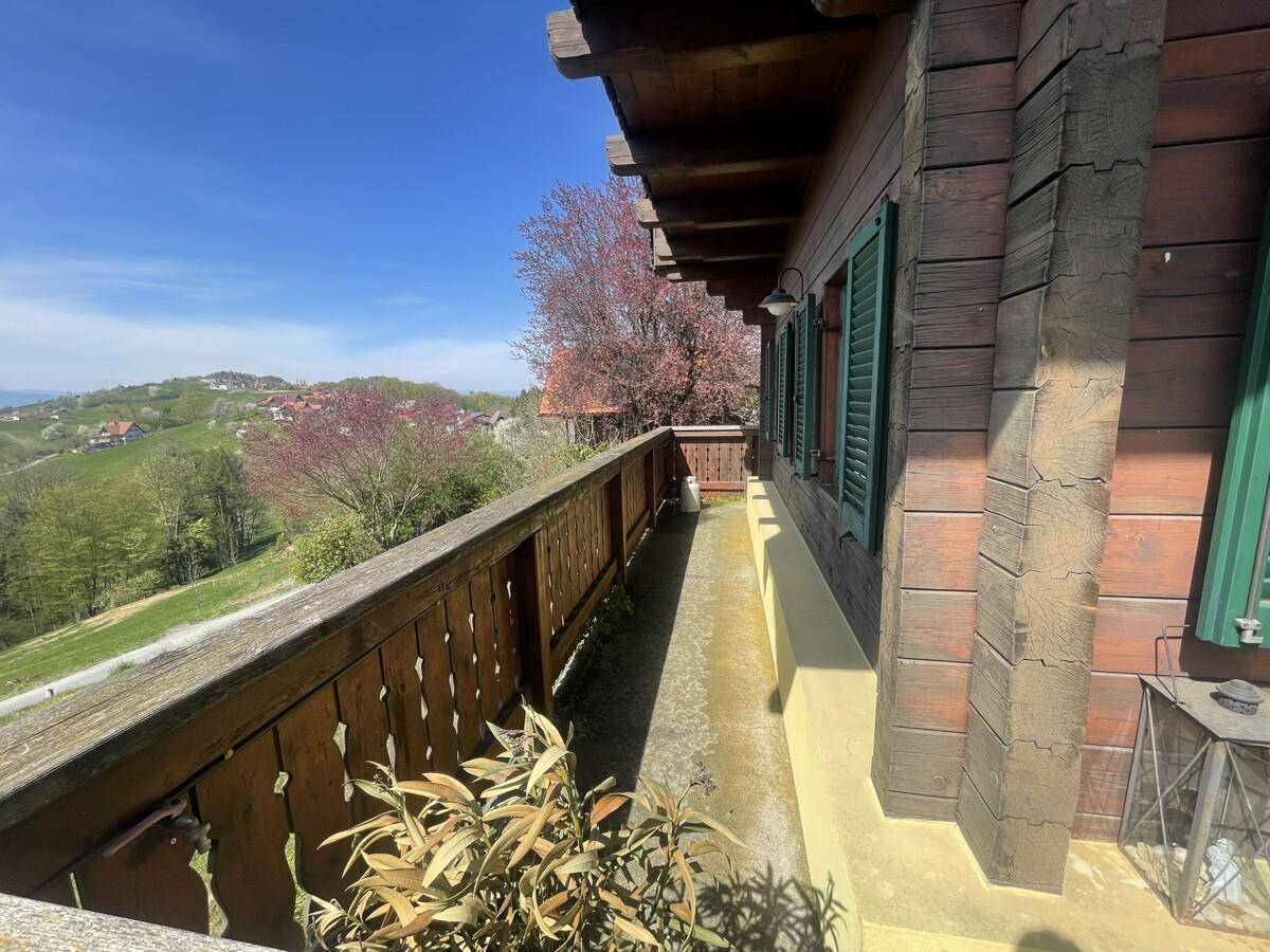 Traditioneller Holzbalkon mit Blick auf die grüne Umgebung und das Haus.