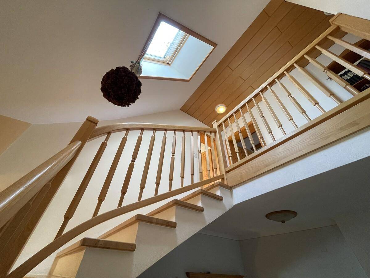 Helle Holztreppe mit Geländer und Dachfenster für natürliches Licht.