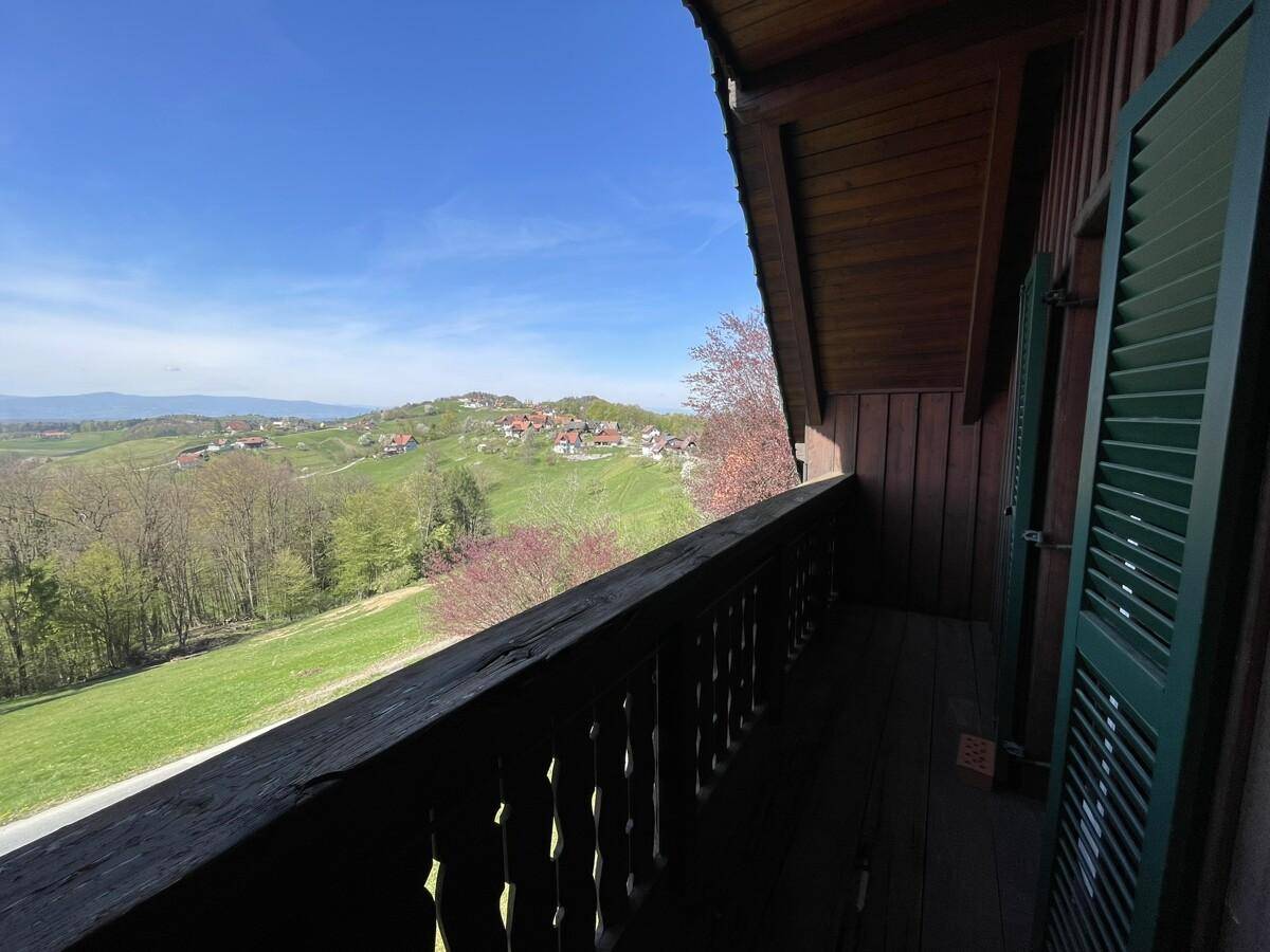Langer Holzbalkon mit traditionellem Geländer und weitem Blick ins Grüne.