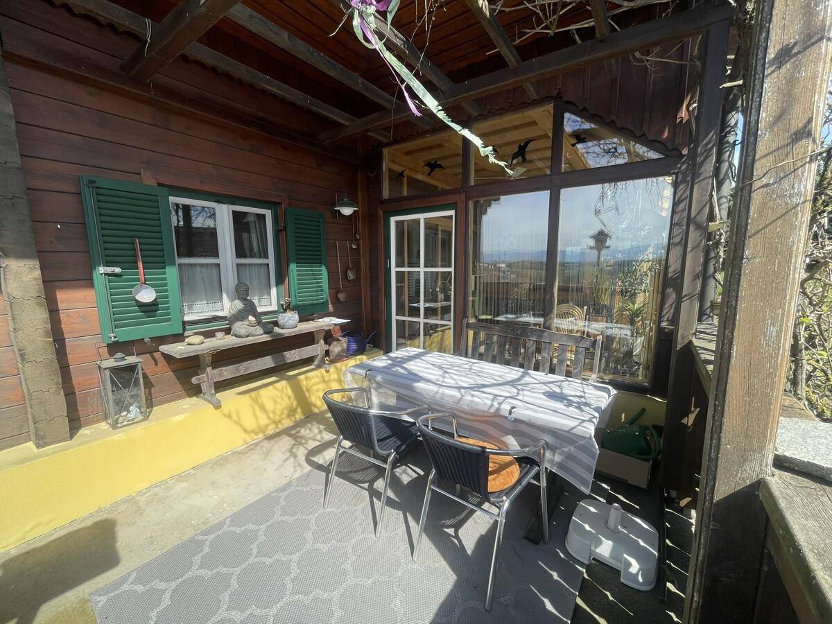 Überdachte Terrasse mit Esstisch und Stühlen, ideal für Mahlzeiten im Freien.