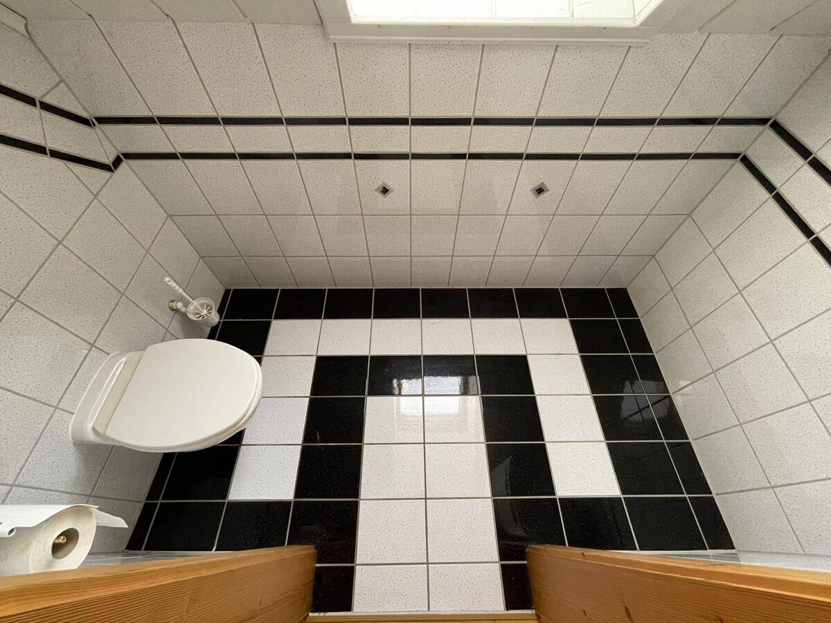 Modernes Gäste-WC mit schwarz-weißem Fliesenboden und Wand-WC.