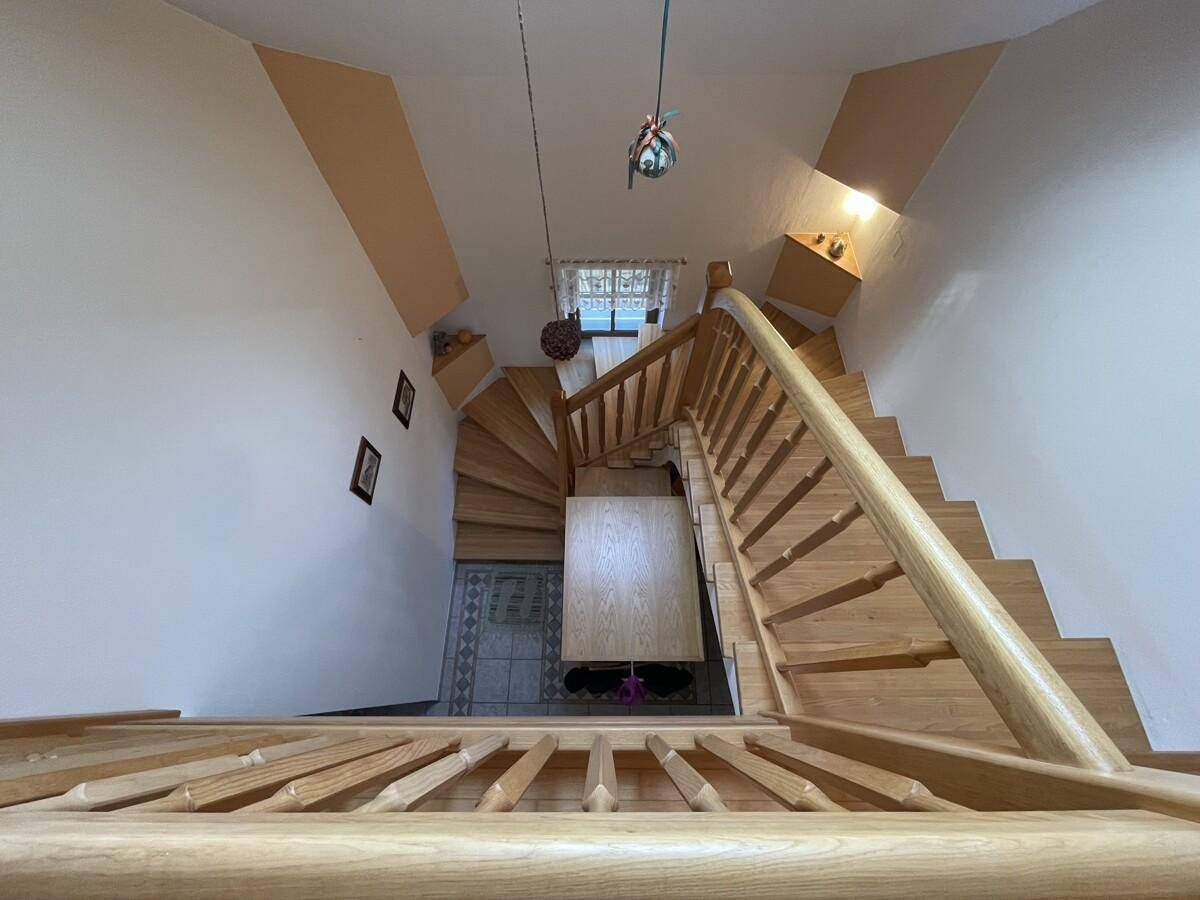 Geschwungene Holztreppe von oben gesehen, die in den unteren Bereich führt.