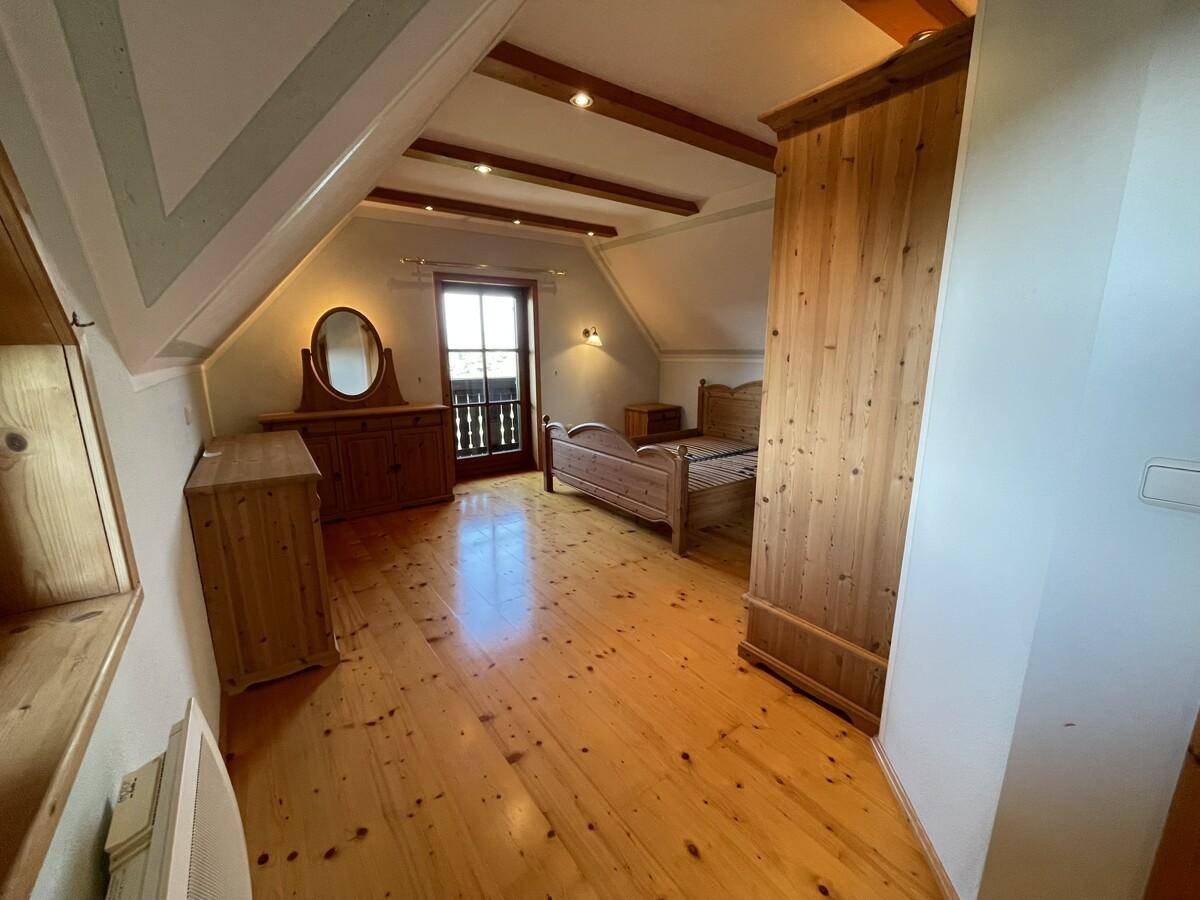Gemütliches Schlafzimmer mit Holzboden, Holzbalken und traditionellen Holzmöbeln.
