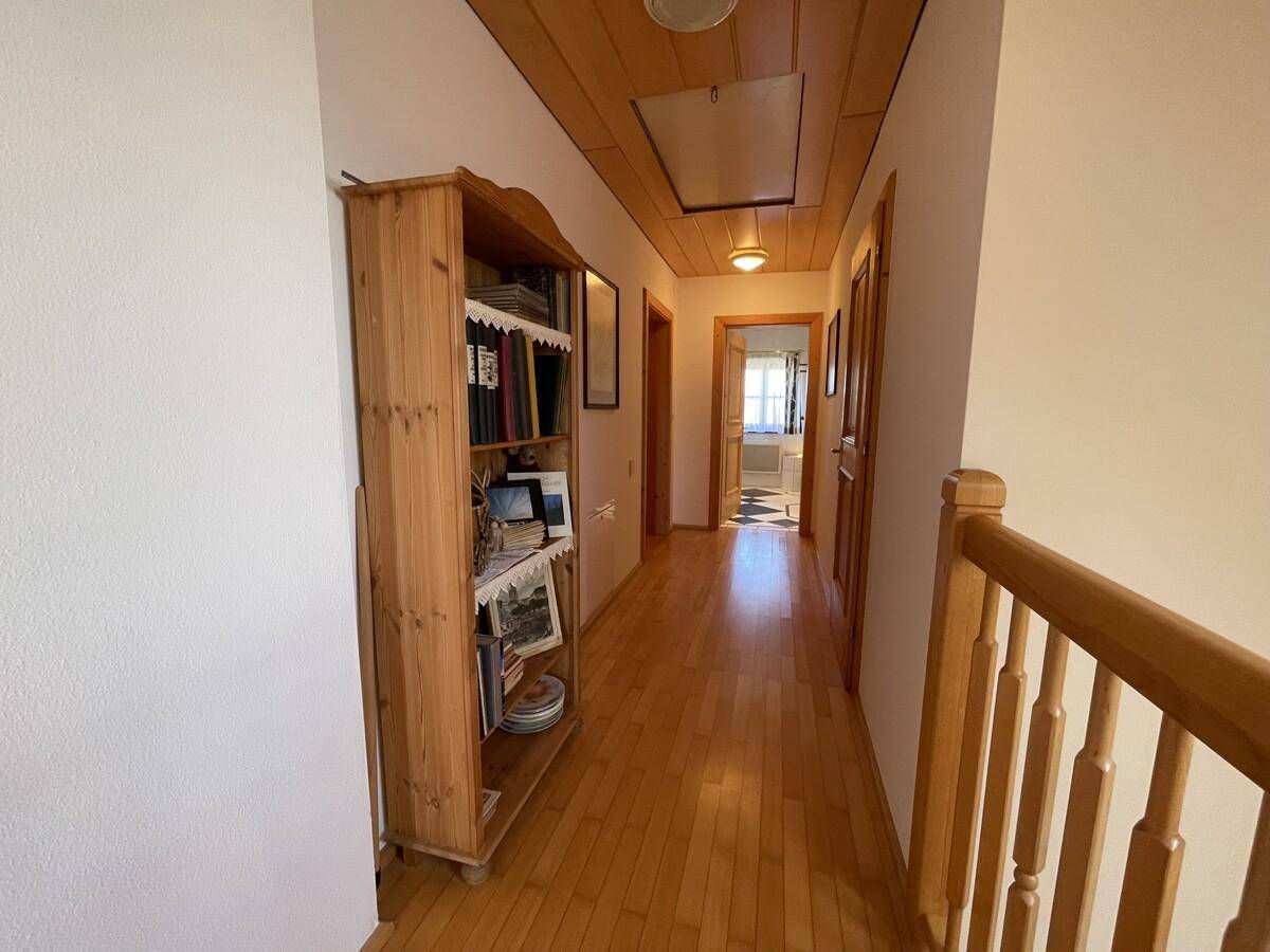 Oberer Flur mit Holzboden, Holzdecke und Bücherregal.