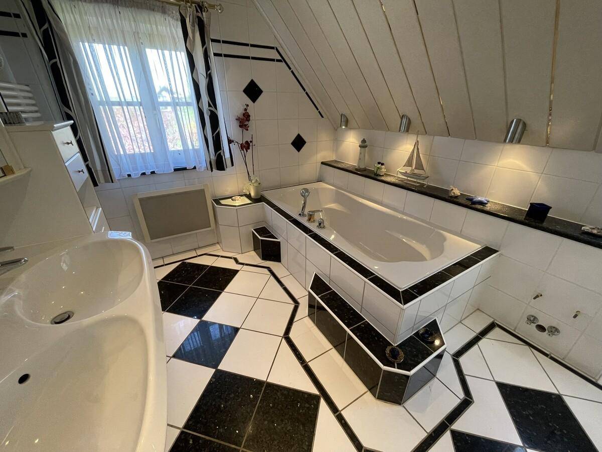Geräumiges Badezimmer mit Badewanne, Waschbecken und markantem Fliesenmuster.