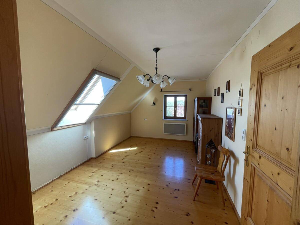 Helles Schlafzimmer mit Holzboden, Dachfenster und traditionellen Möbeln.