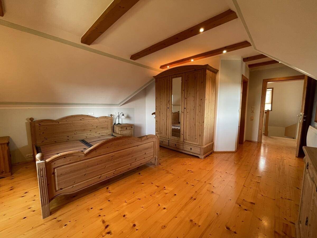 Schlafzimmer mit Holzboden, Holzbett und Kleiderschrank im Landhausstil.