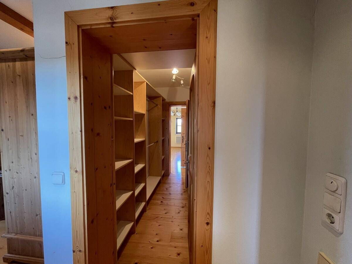 Begehbarer Kleiderschrank mit vielen Regalen und Holzboden.