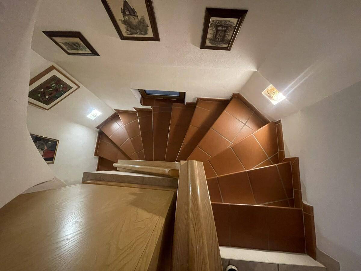 Wendeltreppe mit Fliesenstufen und Holzgeländer, die nach oben führt.