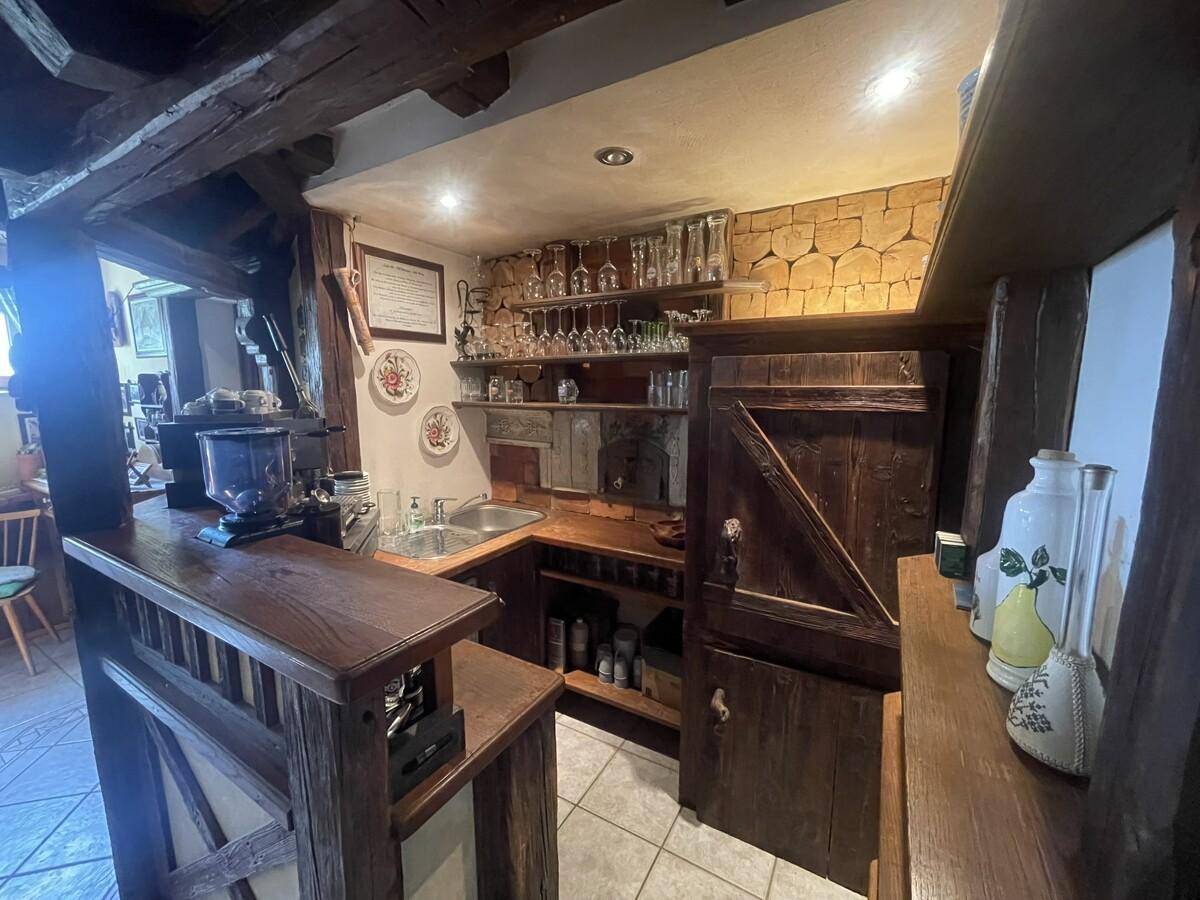 Gemütliche Bar-Ecke mit Holztheke, Spüle und vielen Gläsern.