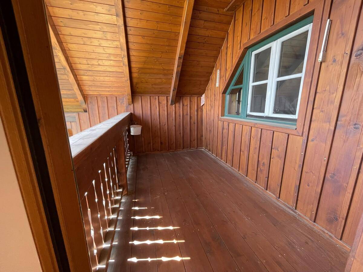 Schmaler Holzbalkon mit Holzverkleidung und Blick ins Grüne.
